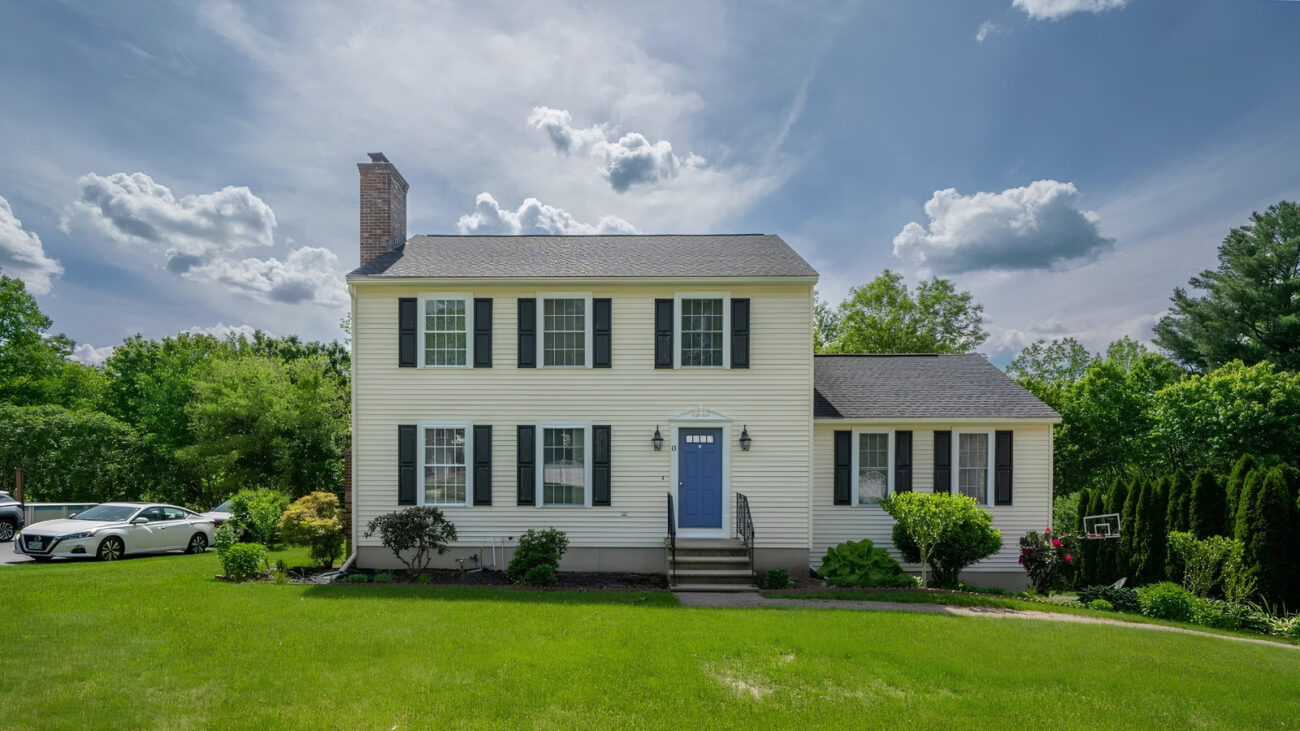 Colonial-style home in Hooksett, New Hampshire, with black shutters, a blue front door, and landscaped front lawn
