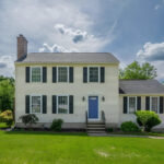 Colonial-style home in Hooksett, New Hampshire, with black shutters, a blue front door, and landscaped front lawn